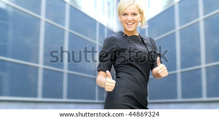 Young attractive business woman showing signs of success over modern background