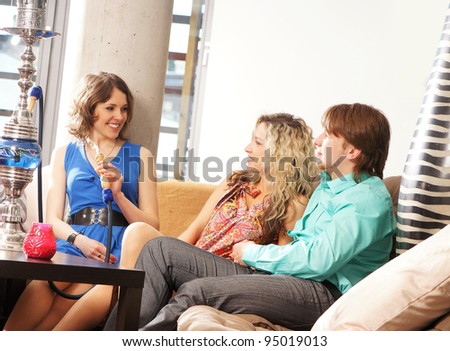 Group of young and sexy people smoking hookah in the lounge