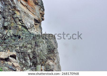 female hiker on a steep alpine trail in heavy fog, side view