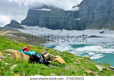 female hiker resting by the Grinnell glacier in Many Glaciers, Glacier National Park, Montana in summer