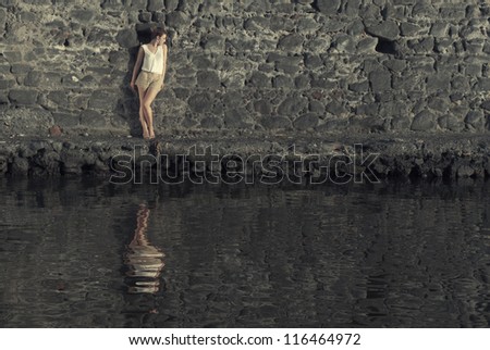 Young woman against the wall with reflection in the water