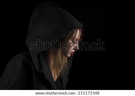 Portrait Of Beautiful Young Woman Wearing Black Hood Over Black Background