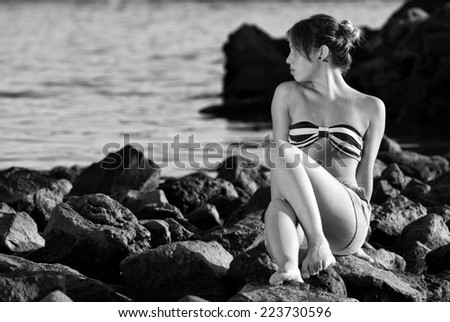 Thinking woman on the rocks near the sea black and white