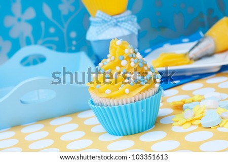 Blue and yellow cupcake with tools in the background