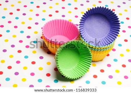 empty cupcake cases on a colorful dotted background