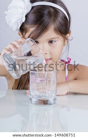 beautiful long-haired girl pours water from a beaker to another