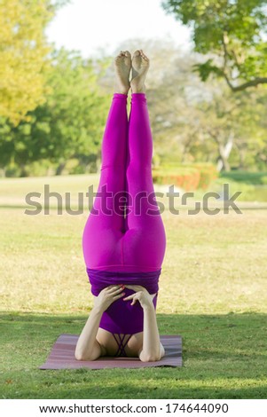 Woman in Fuchsia sport clothes doing a yoga position in a natural park