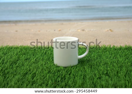 White coffee mug on the grass in beach