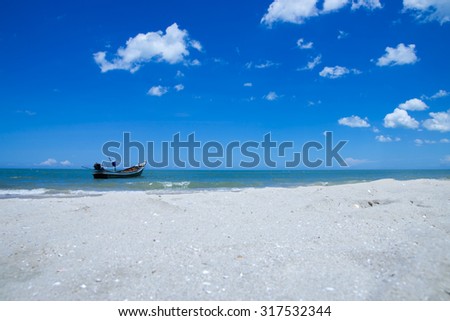 Fishing boat on the beach with blue sky and sand.