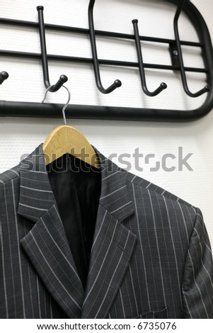 Man\'s jacket hanging on a coat hanger at a wall