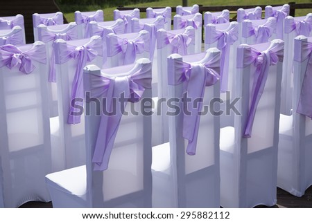 Beautiful wedding event decoration. Violet bow on the chairs