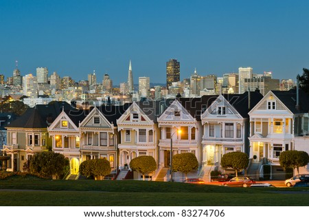 Painted Ladies with San Francisco skyline in the background as seen from Alamo Square with city lights