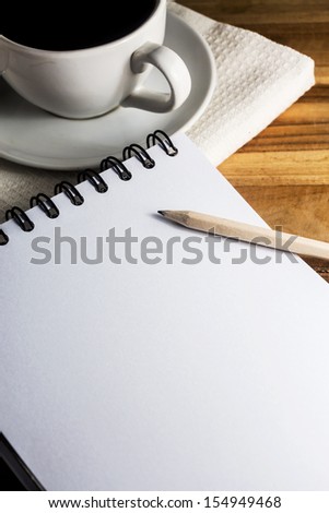 work desk with  paper, pencil and white cup of coffee