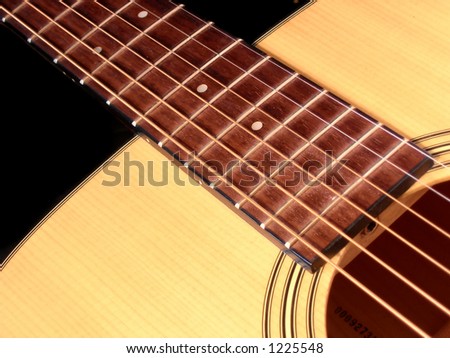 Close up of an acoustic guitar. Strings frets and sound hole.