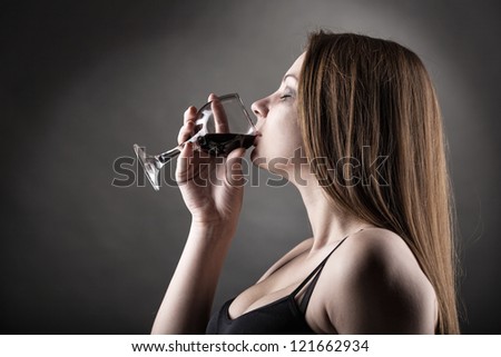 Young beautiful woman in depression, drinking alcohol on dark background