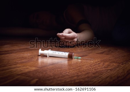Close-up on the floor of the syringe with the drug. In the background, a young drug addict
