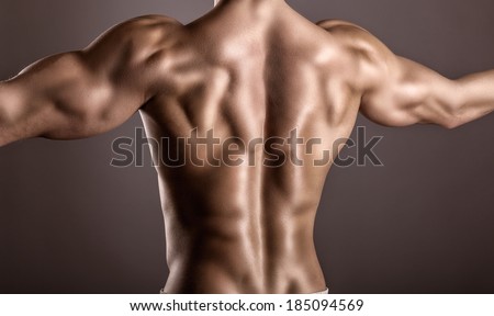 Strong athletic man back on a gray background