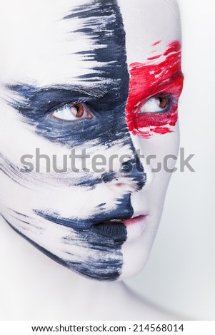 Close-up face of a beautiful woman with white makeup and red and black stripes paint