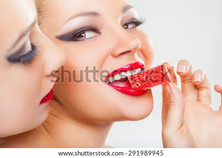 Close-up of a face of two lesbian girlfriends with candied fruit jelly on a light background
