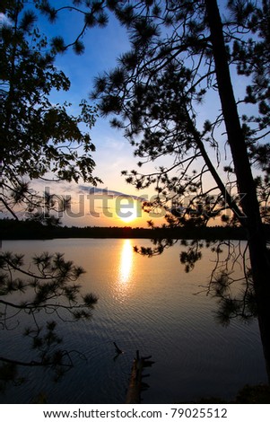 Beautiful sunset seen through pine trees over a northwoods Wisconsin lake.