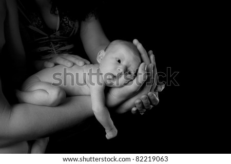 Black and White image of a baby being held by her parents.