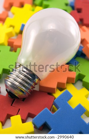 A colorful picture of puzzle pieces and light bulb (off). Could represent the start of solving of a difficult puzzle.