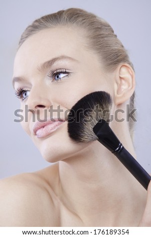 beautiful and young woman with makeup brush in hand