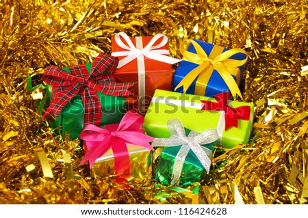 Five colorful gifts on gold tinsel.(horizontal) Many gifts wrapped colorful paper and ribbon.