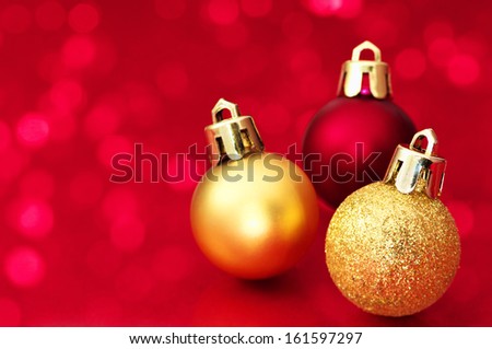 Small Christmas balls on red sparkle background. Christmas decorations on red background.