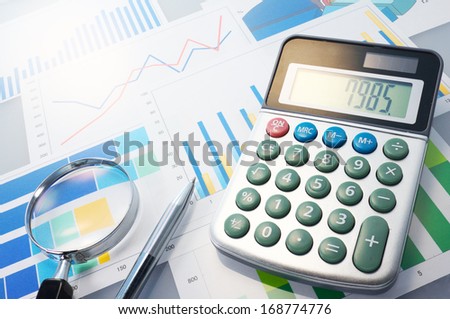 Graphs, calculator, magnifier and pen. Analyzing finances.