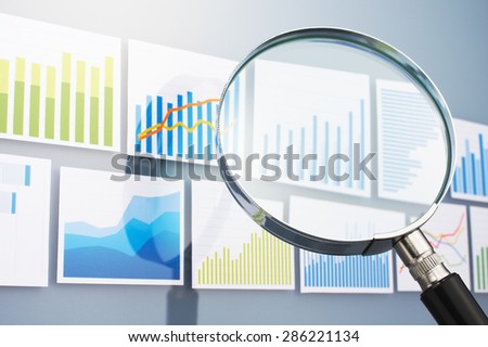 Many graphs and magnifying glass on gray background. Searching and analyzing data with magnifying glass. Situation analysis.