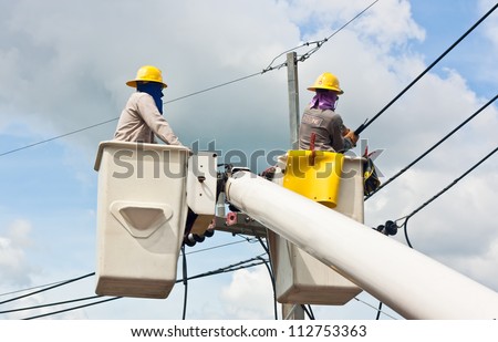 An electrical utility worker in a bucket fixes a problem with a power line.