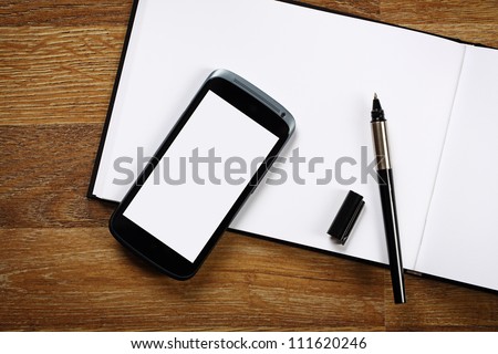 Top view on notebook, smartphone and pen on wooden office desk.