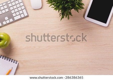 Office equipment such as pc keyboard, tablet, mouse and notebook on wooden office desk.