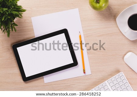 Office equipment such as digital tablet, computer mouse and keyboard, paper and pencil on office wooden desk.