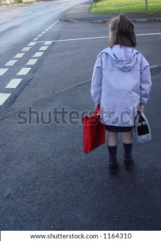 Child on her way to school, getting ready to cross the street.