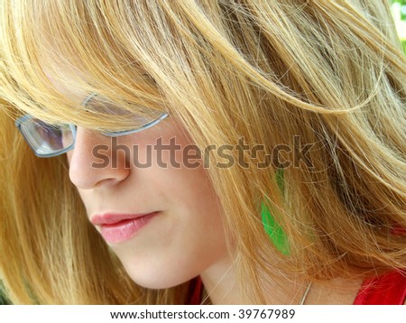 A profile of a blond woman with spectacles, with her long locks obscuring part of her face.