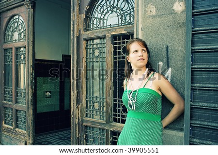 A pretty teenage girl standing outside the entrance to an old building.