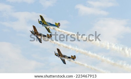 BUCHAREST, ROMANIA - OCTOBER 4, 2014. Aerobatic airplane pilots training in the sky of the city. Colored airplanes with trace smoke.