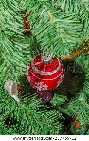 Detail of green Christmas (Chrismas) tree with colored ornaments, globes, stars, Santa Claus, Snowman, red boots, shoes, candles, bells, white transparent angels, snow flakes and candy sticks