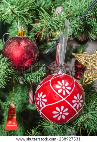 Detail of green Christmas (Chrismas) tree with colored ornaments, globes, stars, Santa Claus, Snowman, red boots, shoes, candles, bells, white transparent angels, snow flakes and candy sticks