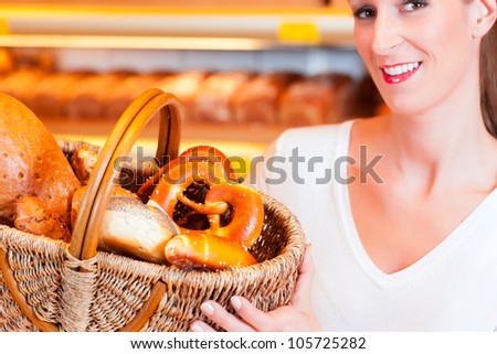 Female baker or saleswoman in her bakery with fresh pastries and bakery products