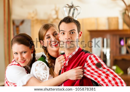 Young people in traditional Bavarian Tracht in restaurant or pub having fun and making jokes