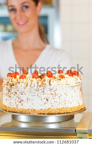 Female baker or pastry chef with black forest cake in bakery