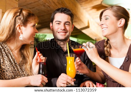 Young happy people drinking cocktails in bar or restaurant; presumably it is a little party
