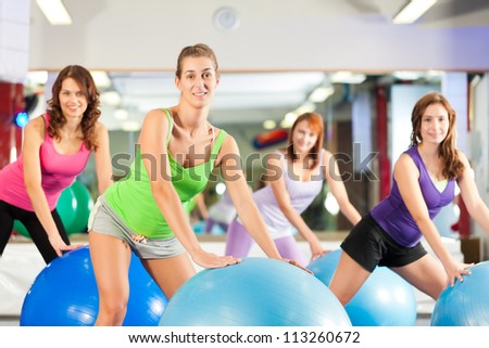 Fitness - Young women doing sports training or workout with gymnastic ball in a gym