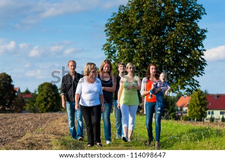 Family and multi-generation - mother, father, children and grandmother having fun on meadow in summer