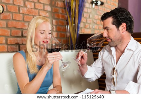 Attractive young couple drinking red wine in restaurant or bar, it might be the first date