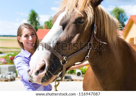 Young woman in the stable with horse, caring and is happy