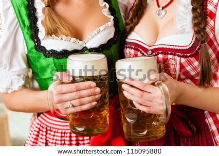 Two young women in traditional Bavarian Tracht in restaurant or pub with beer and beer stein